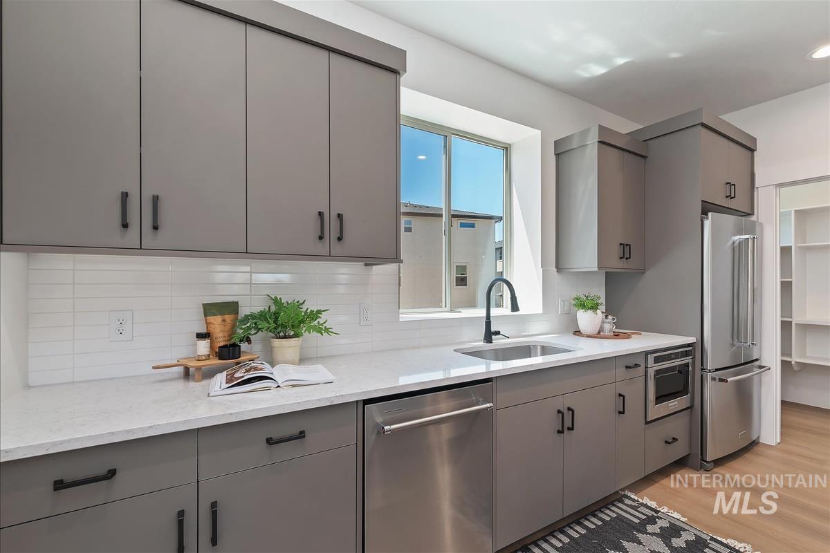 1703 South Federal Way Boise, ID 83705 - Photo 3 of 38 Kitchen featuring gray cabinetry, stainless steel appliances, light stone counters, and light wood-style flooring