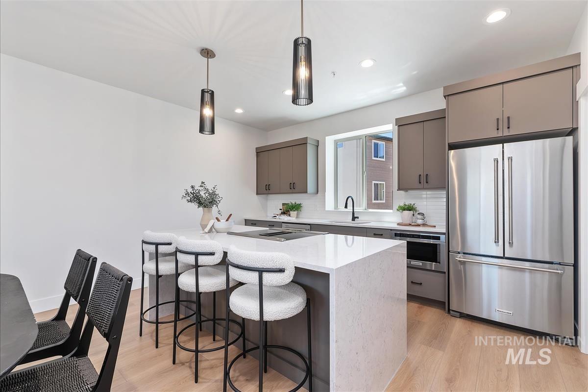 1703 South Federal Way Boise, ID 83705 - Photo 7 of 38 Kitchen with stainless steel appliances, decorative backsplash, pendant lighting, a breakfast bar, and light wood finished floors
