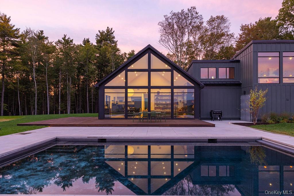 Pool at dusk featuring a patio, an outdoor pool, and a yard