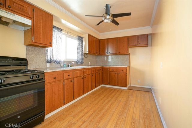 a kitchen with a sink a stove cabinets and wooden floor