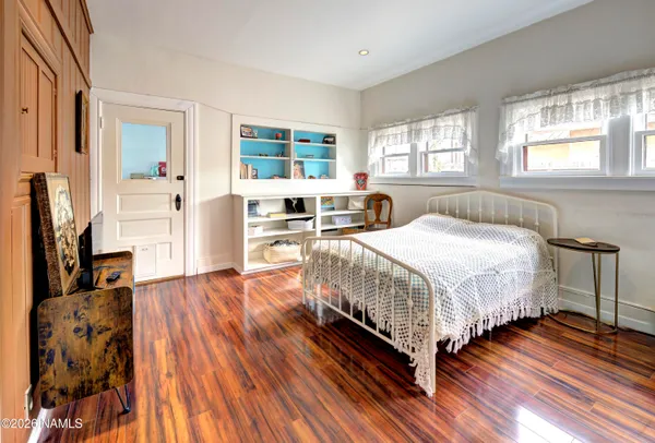 a spacious bedroom with a bed and wooden floor