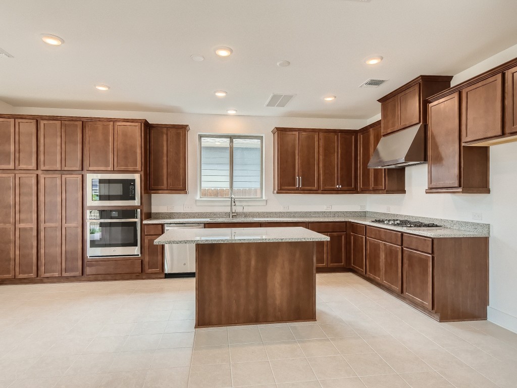 9101 Spire View Austin, TX 78744 - Photo 11 of 29 a large kitchen with stainless steel appliances wooden cabinets a stove and a refrigerator