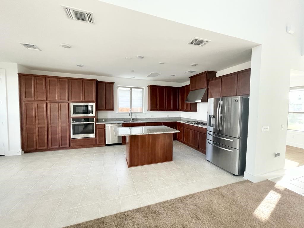 9101 Spire View Austin, TX 78744 - Photo 9 of 29 a kitchen with stainless steel appliances kitchen island granite countertop a refrigerator oven a sink and dishwasher