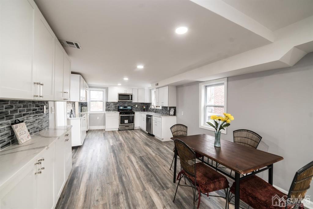 8 Main Street Matawan, NJ 07747 - Photo 9 of 36 a kitchen with a table chairs a sink dishwasher stove and cabinets with wooden floor
