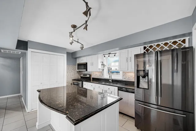 a kitchen with stainless steel appliances granite countertop a sink a refrigerator and a granite counter tops