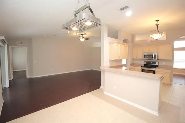 a kitchen with stainless steel appliances kitchen island granite countertop a refrigerator a stove and a sink with wooden floor