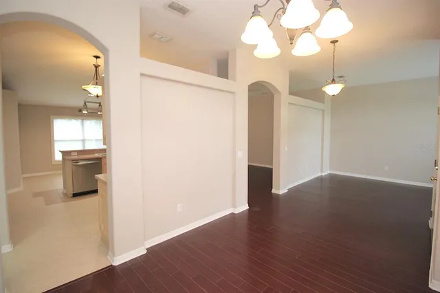 a view of a room with wooden floor and a chandelier fan