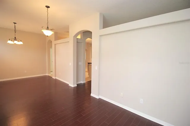 an empty room with wooden floor and ceiling fan