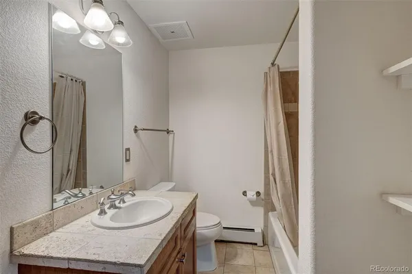 a bathroom with a granite countertop sink toilet and a mirror