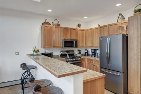 a kitchen with granite countertop a refrigerator and a stove top oven