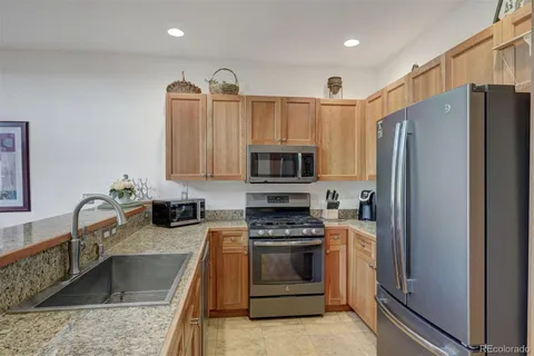 a kitchen with granite countertop a refrigerator stove and sink