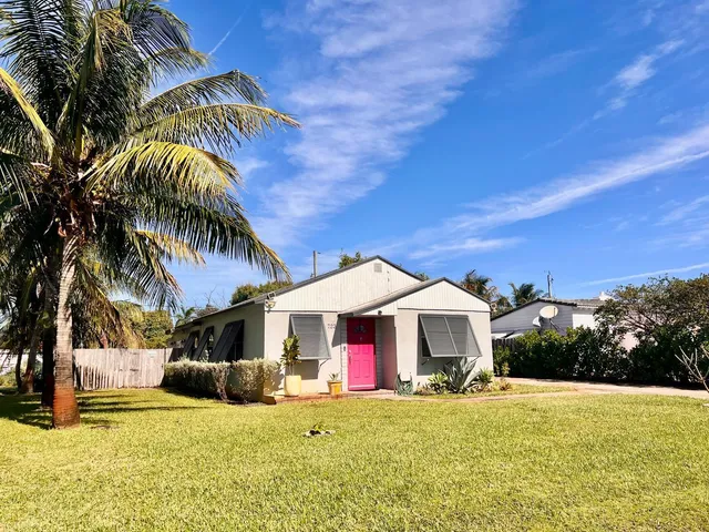 a front view of a house with a garden and trees
