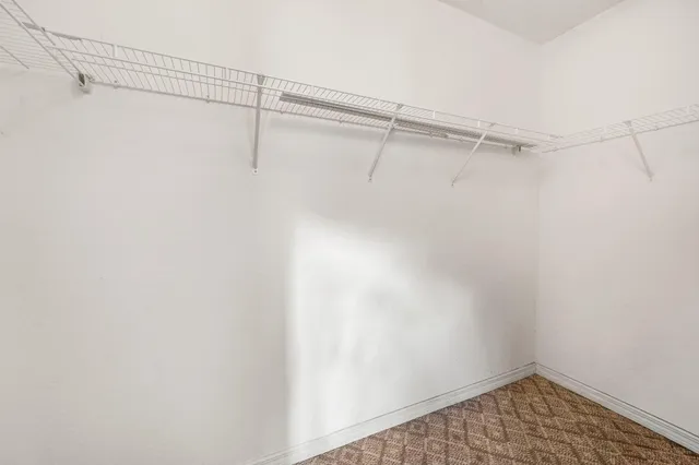 an empty room with a chandelier fan and windows