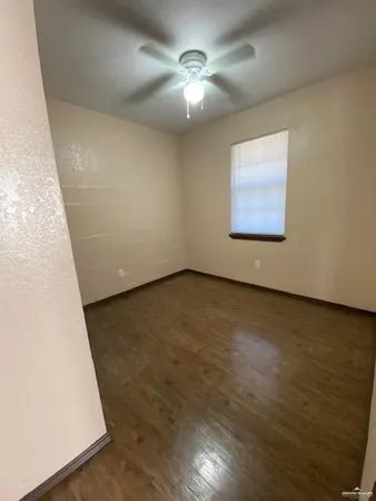 an empty room with a ceiling fan and wooden floor