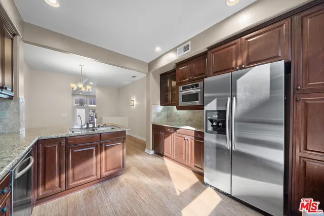 a kitchen with stainless steel appliances kitchen island granite countertop a refrigerator a stove and a sink
