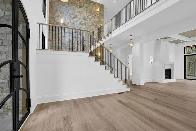 a view of an empty room with wooden floor fireplace and a window