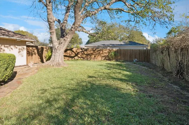 a view of yard with large tree and wooden fence