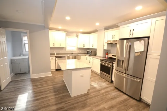 a kitchen with stainless steel appliances a refrigerator a sink and white cabinets
