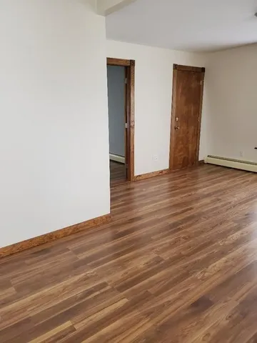 a view of an empty room with wooden floor and closet