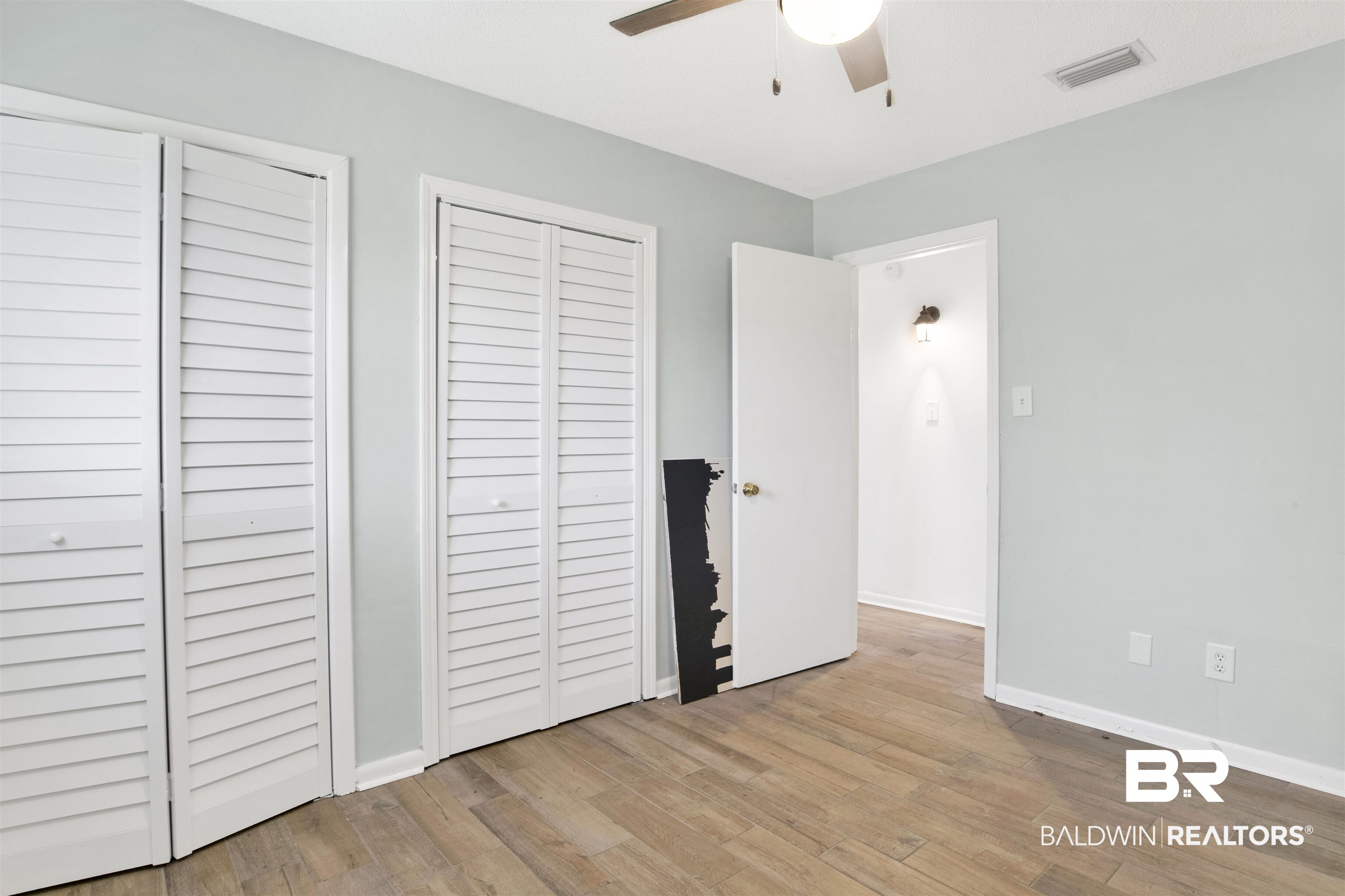 10244 Magnolia Road Irvington, AL 36544 - Photo 11 of 37 Unfurnished bedroom featuring multiple closets, visible vents, baseboards, ceiling fan, and wood finished floors