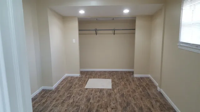a view of empty room with wooden floor and fan