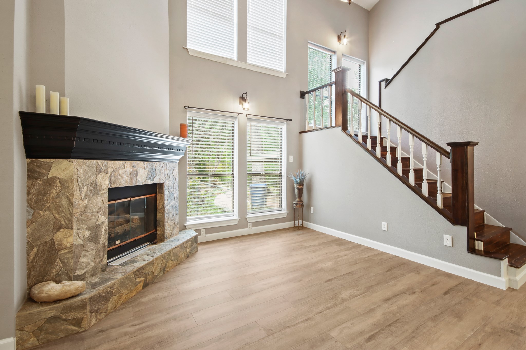 35 Susan Drive Cleveland, TX 77327 - Photo 4 of 33 This inviting living space features a stone fireplace, high ceilings, and large windows that provide plenty of natural light. The elegant staircase with wooden railings adds a touch of sophistication. Perfect for cozy gatherings and bright, open living.
