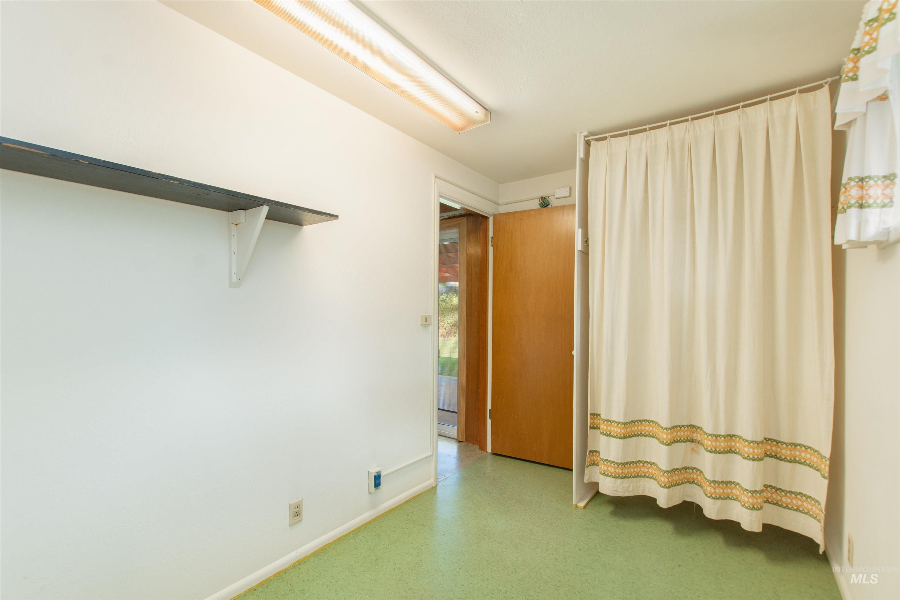 2716 North Redway Road Boise, ID 83704 - Photo 27 of 36 Wall-mounted shelving with support brackets, wood-finish door, overhead fluorescent lighting, and light green flooring