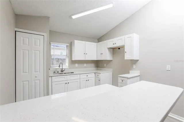 a large white kitchen with sink and cabinets