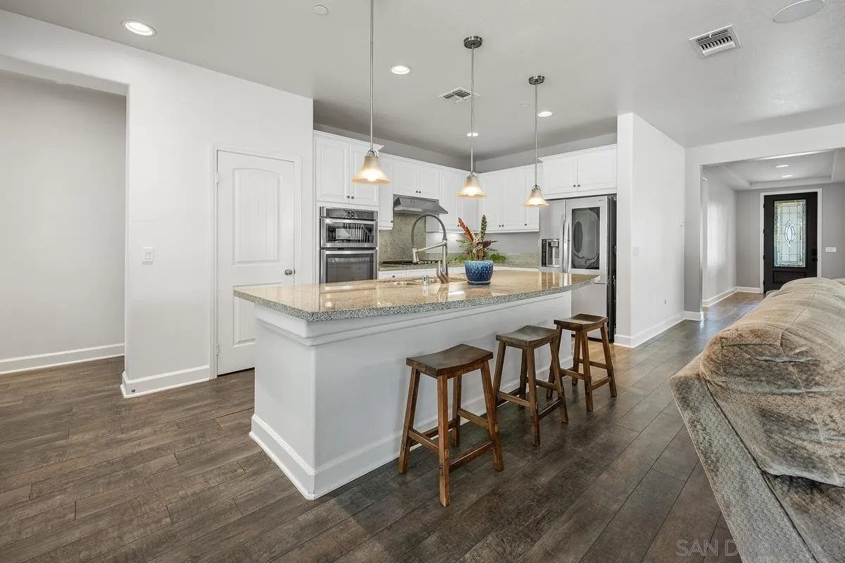 529 Adobe Estates Drive Vista, CA 92083 - Photo 4 of 39 a kitchen with stainless steel appliances kitchen island granite countertop a stove a sink a refrigerator and a dining table