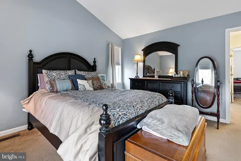 a bedroom with a bed and a dresser with mirror