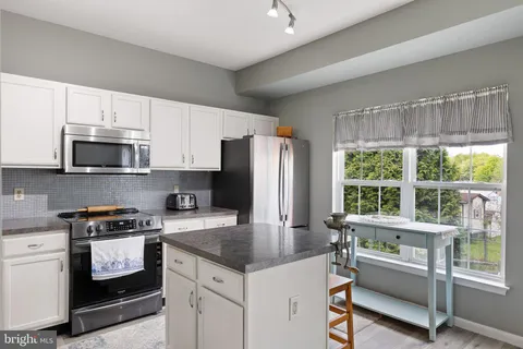 a kitchen with granite countertop a stove a sink and a refrigerator