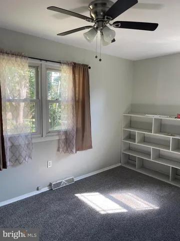 an empty room with a ceiling fan and a window