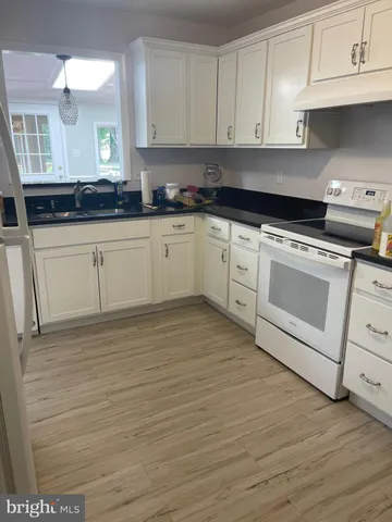 a view of a refrigerator in kitchen and an empty room