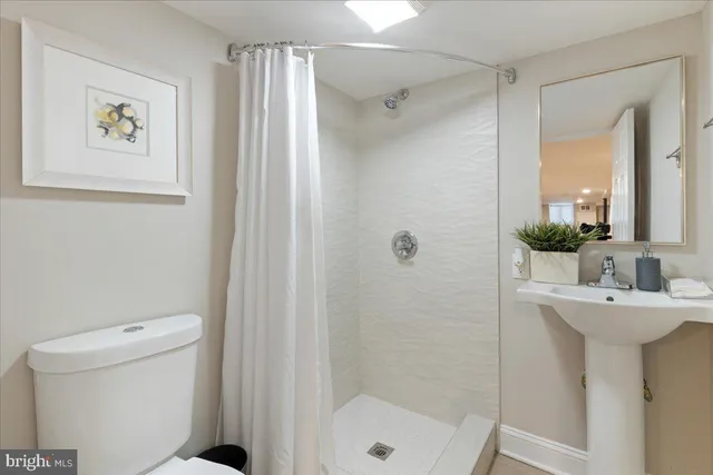 a bathroom with a sink a mirror a toilet and shower