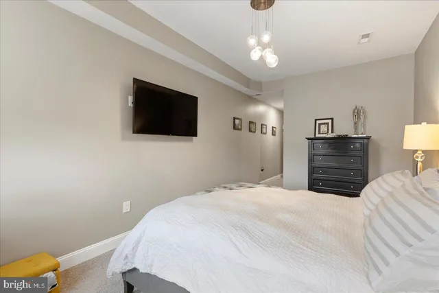 a bedroom with a bed a dresser and a flat screen tv