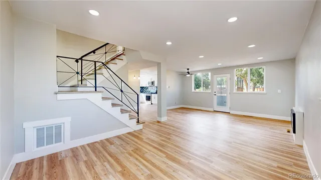 an empty room with wooden floor and windows