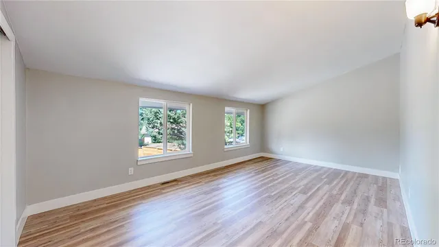 an empty room with wooden floor and windows