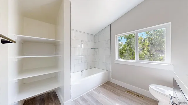 a view of an empty room with wooden floor and windows