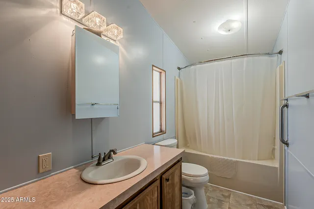 a bathroom with a sink a toilet a mirror and shower curtain