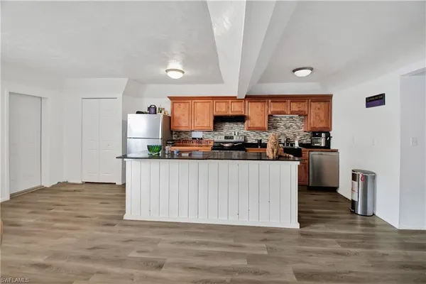 a kitchen with stainless steel appliances a refrigerator a sink dishwasher and a stove with wooden floor