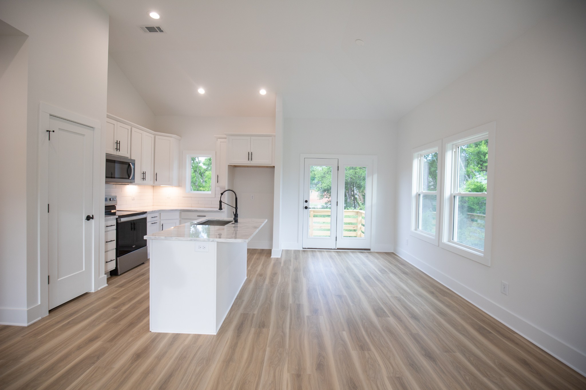 308 Larkin Springs Road Madison, TN 37115 - Photo 11 of 25 a kitchen with kitchen island wooden floors white cabinets and stainless steel appliances
