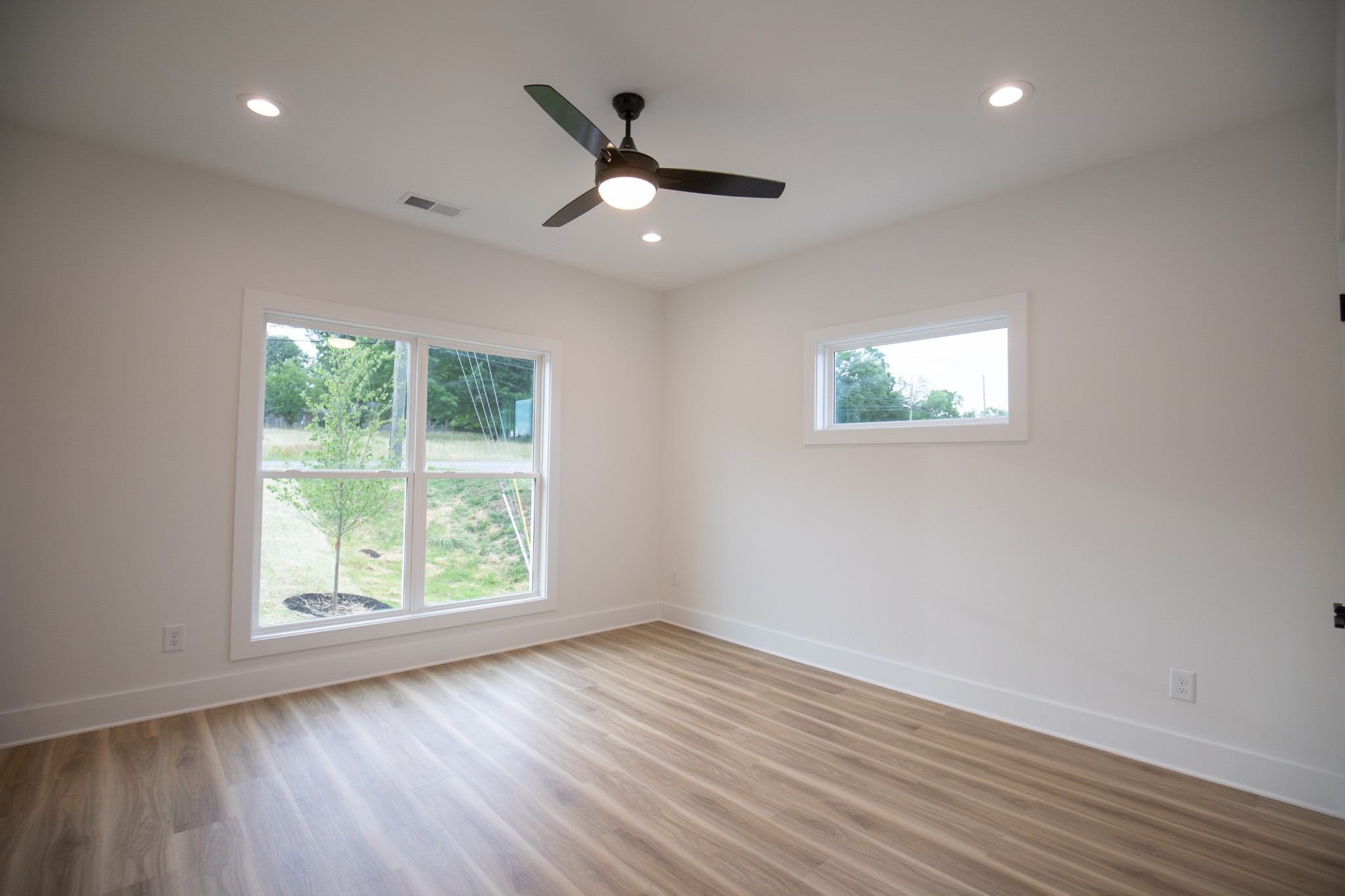 308 Larkin Springs Road Madison, TN 37115 - Photo 19 of 25 an empty room with wooden floor ceiling fan and windows