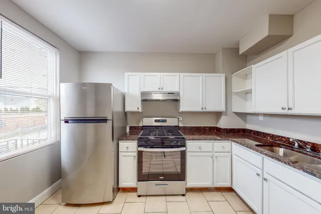 a kitchen with a refrigerator a stove a sink and white cabinets