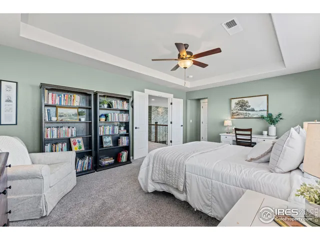 a bedroom with a large bed a chandelier and a book shelf