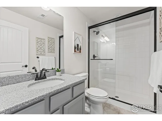 a bathroom with a granite countertop sink toilet a mirror and shower
