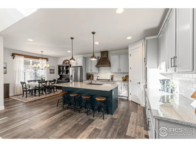 a room with stainless steel appliances kitchen island granite countertop furniture and wooden floor