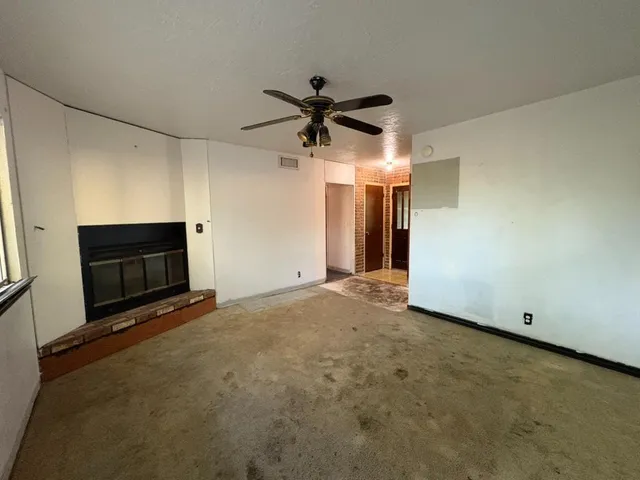 a view of a livingroom with a fireplace and a ceiling fan