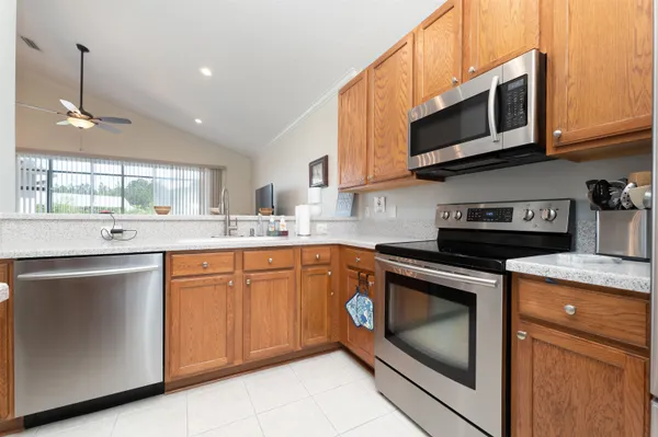 a kitchen with stainless steel appliances granite countertop a sink a stove a microwave and wooden cabinets