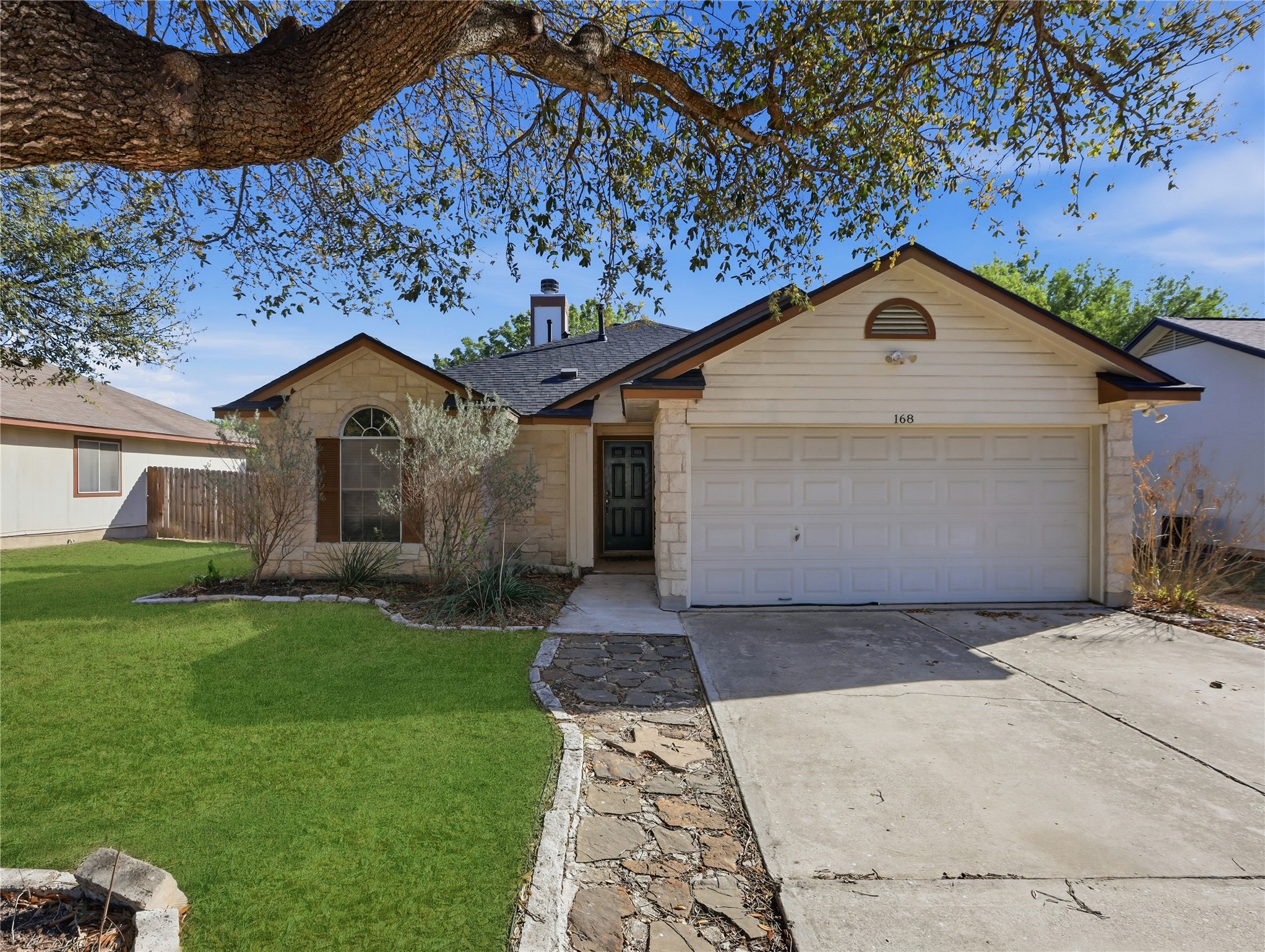 168 Keystone Loop Kyle, TX 78640 - Photo 2 of 23 Ranch-style home featuring stone siding, driveway, a front yard, a garage, and a shingled roof