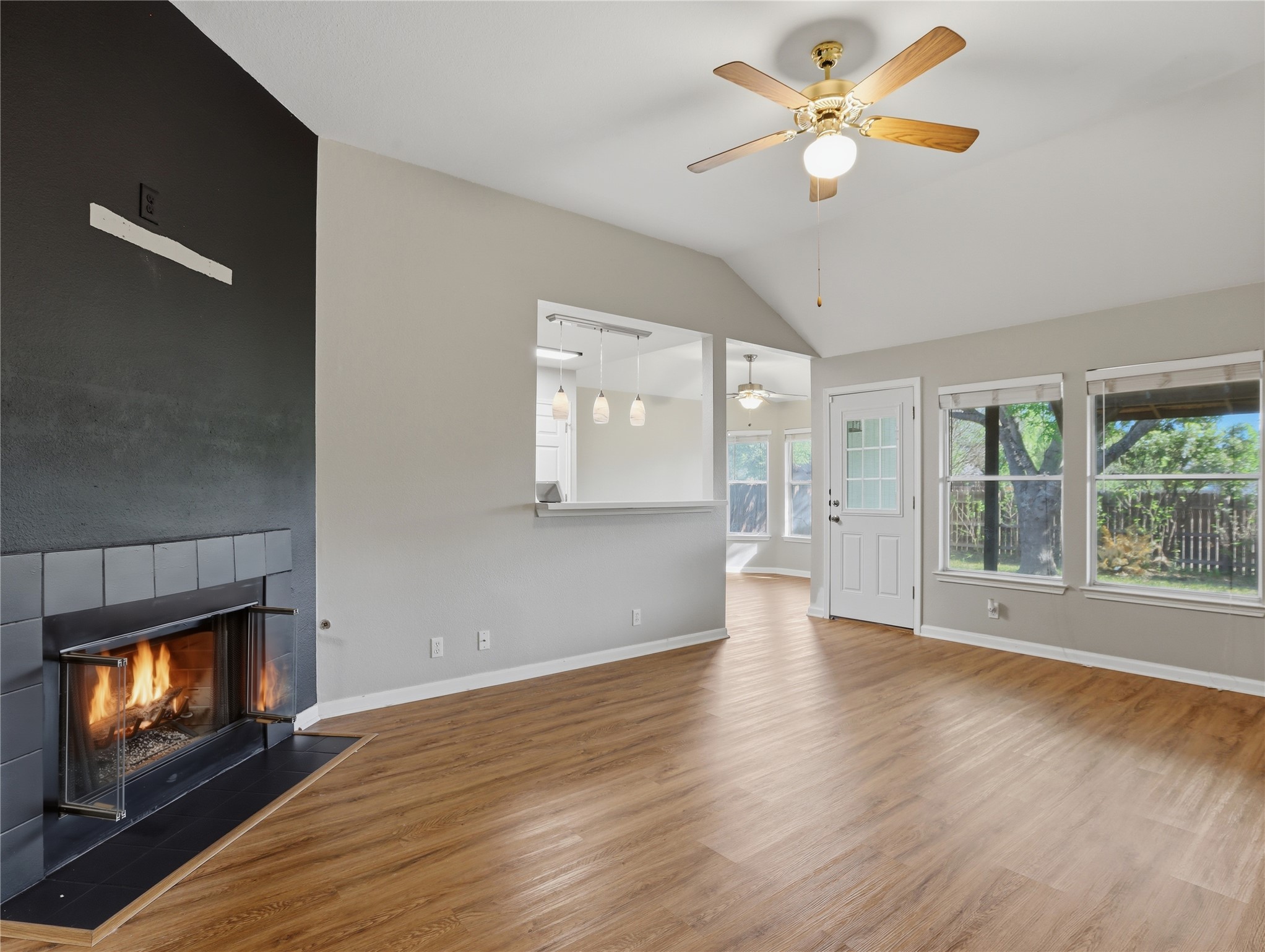 168 Keystone Loop Kyle, TX 78640 - Photo 5 of 23 Unfurnished living room featuring wood finished floors, vaulted ceiling, a large fireplace, and a ceiling fan